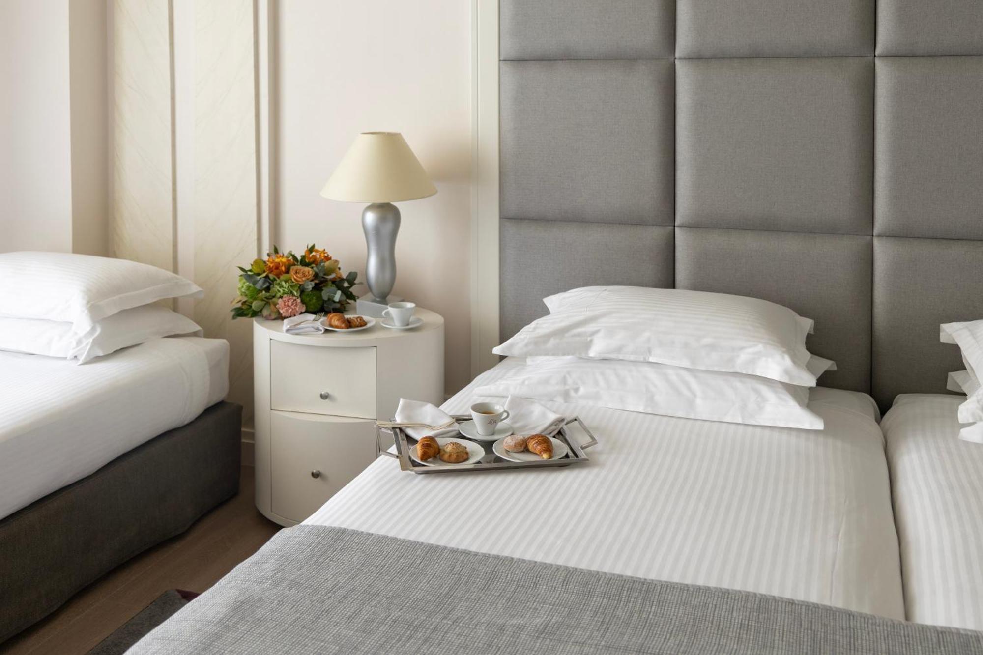 Njv Athens Plaza Hotel Bagian luar foto A bed with a nightstand